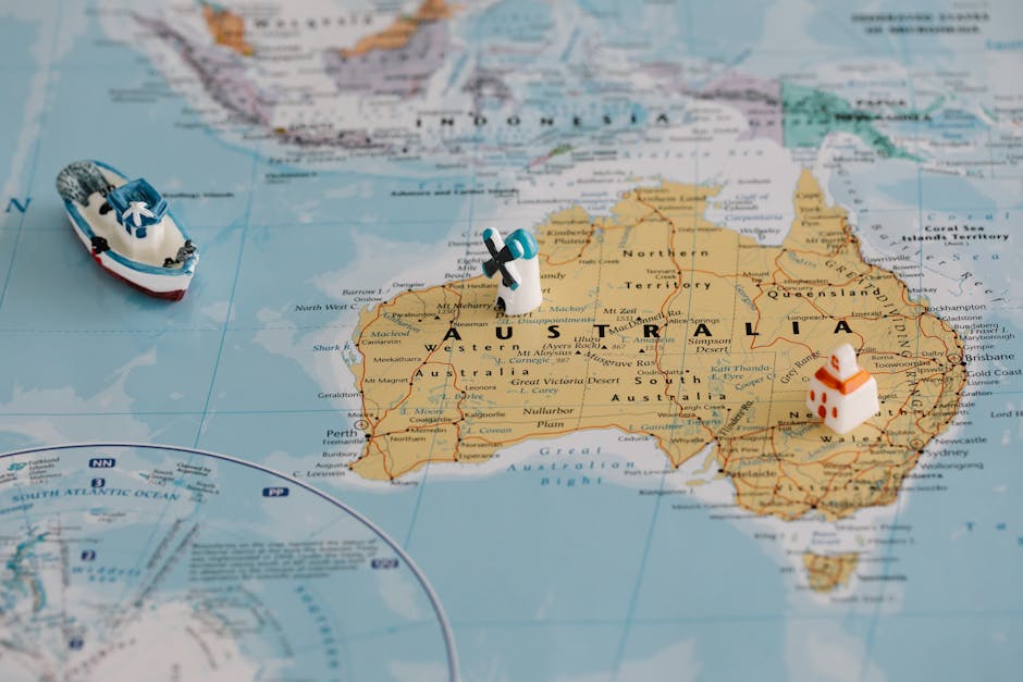 Miniature windmill and ship placed atop a map of Australia, highlighting travel concepts.